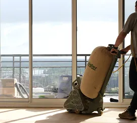 Ponçage de parquet à la machine devant une baie vitrée