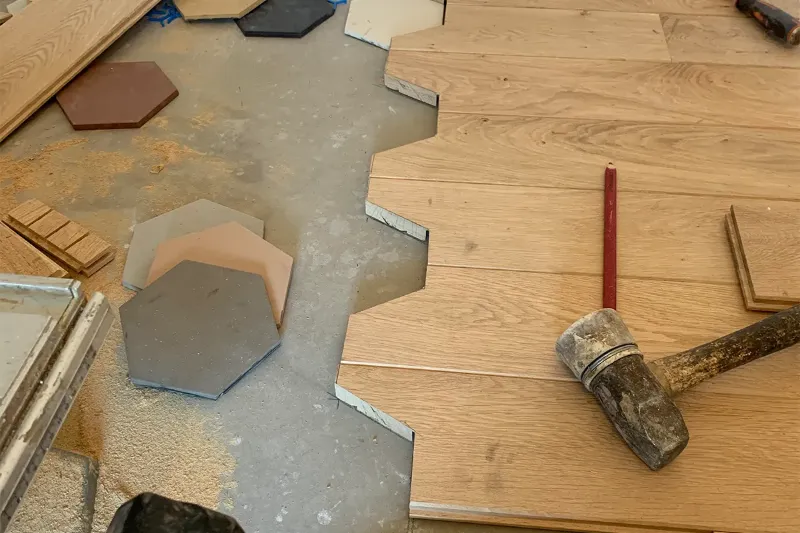 Pose de parquet en cours contre un carrelage hexagonal, chantier à Lyon